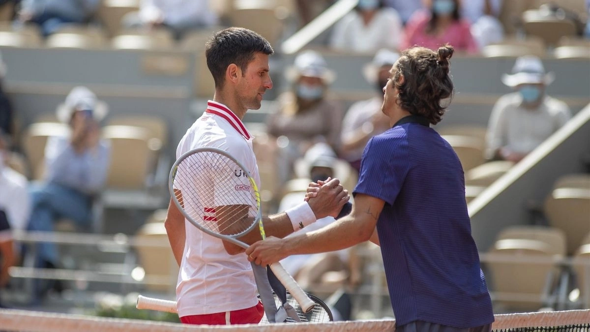 Musetti (phải) bắt tay Djokovic sau khi bỏ cuộc ở vòng bốn Roland Garros 2021. Ảnh: Reuters