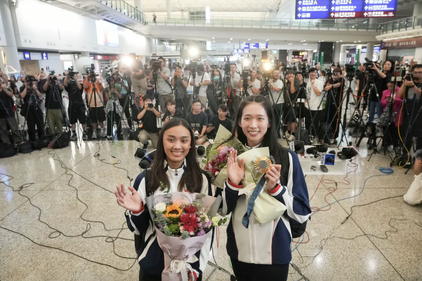 Vivian Kong (phải) được báo chí săn đón tại sân bay Hong Kong sáng 1/8. Ảnh: SCMP