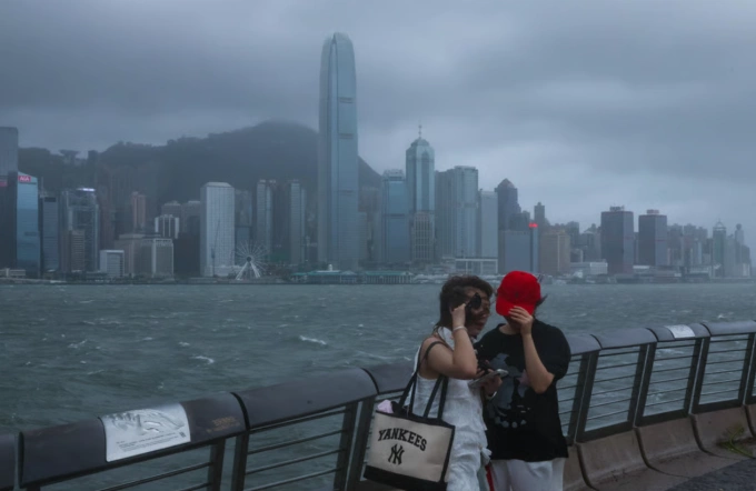 Hai người chụp ảnh bên bờ biển Tsim Sha Tsui sau khi có cảnh báo bão cấp 10. Ảnh: Edmond So