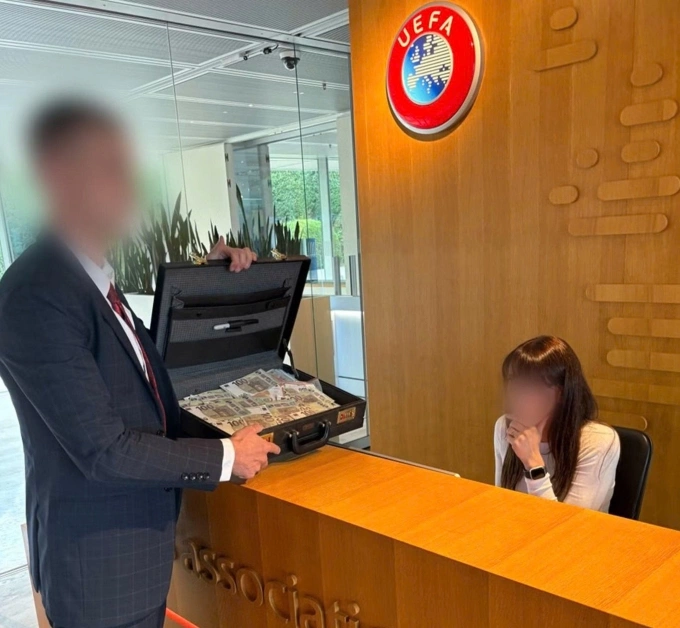 Đại diện CĐV Palace mở vali đựng tiền giả trên quầy lễ tân trụ sở UEFA tại Nyon, Thụy Sĩ ngày 22/7. Ảnh: Holmesdale Fanatics