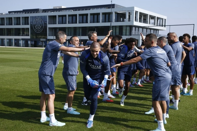 HLV Enrique (thứ ba, hàng bên trái) cùng các thành viên đội một PSG chào đón Chevalier (giữa) trong buổi tập đầu tiên của thủ môn tân binh này hôm 9/8. Ảnh: psg.fr