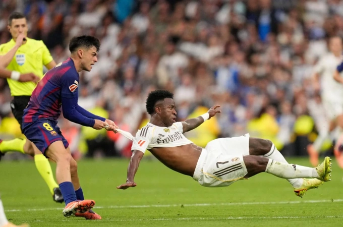 Pedri (trái) kéo áo Vinicius trong trận Barca thua Real 1-2 ở vòng 10 La Liga trên sân Bernabeu, Madrid, Tây Ban Nha ngày 26/10/2025. Ảnh: EPA