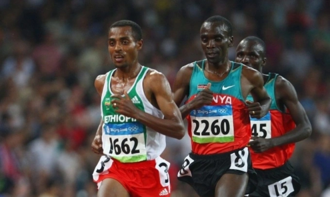 Bekele (bib 2662) chạy trước Kipchoge (2260) trên đường chạy 5.000m nam Olympic 2008. Ảnh: Runners World