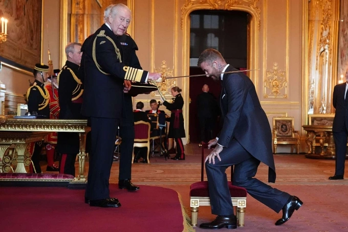 Beckham quỳ gối khi nhận tấn phong từ Nhà vua Vương quốc Anh Charles III ngày 4/11/2025. Ảnh: AP