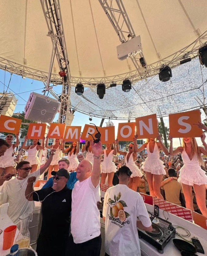 HLV Arne Slot (áo trắng) ăn mừng chức vô địch Ngoại hạng Anh ở Ibiza cuối mùa 2024-2025. HLV Arne Slot (áo trắng) đứng sau bàn DJ tại Ibiza