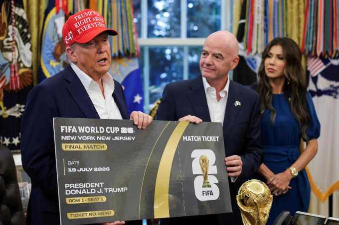 Tổng thống Mỹ Donald Trump và Chủ tịch FIFA Gianni Infantino cầm vé trận chung kết World Cup 2026, với Bộ trưởng An ninh Nội địa Mỹ Kristi Noem đứng phía sau tại Phòng Bầu dục, , Washington D.C., ngày 22/8/2025. Ảnh: Reuters
