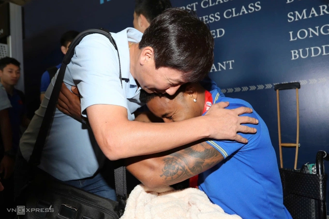 HLV Kim Sang-sik (trái) ôm tiền đạo nhập tịch Nguyễn Xuân Son, đang ngồi xe lăn sau khi gặp chấn thương nặng, ở sân bay Suvarnabhumi ở Bangkok, Thái Lan ngày 6/1/2025, một ngày sau hạ Thái Lan 5-3 ở chung kết ASEAN Cup 2024. Ảnh: Đồng Huy