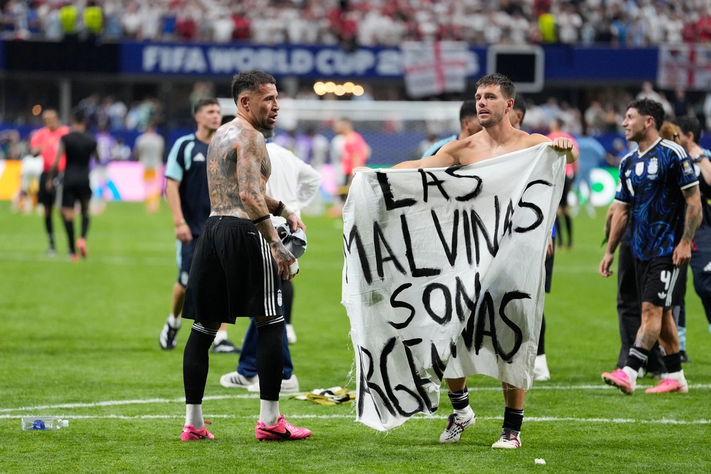 Giovani Lo Celso của Argentina cầm biểu ngữ ghi Quần đảo Malvinas là của Argentina ám chỉ quần đảo Falklands trong khi đồng đội Nicolas Otamendi tiến đến sau trận thắng Anh ở bán kết World Cup 2026 trên sân Atlanta ngày 15/7. Ảnh: AP Giovani Lo Celso cầm biểu ngữ chính trị